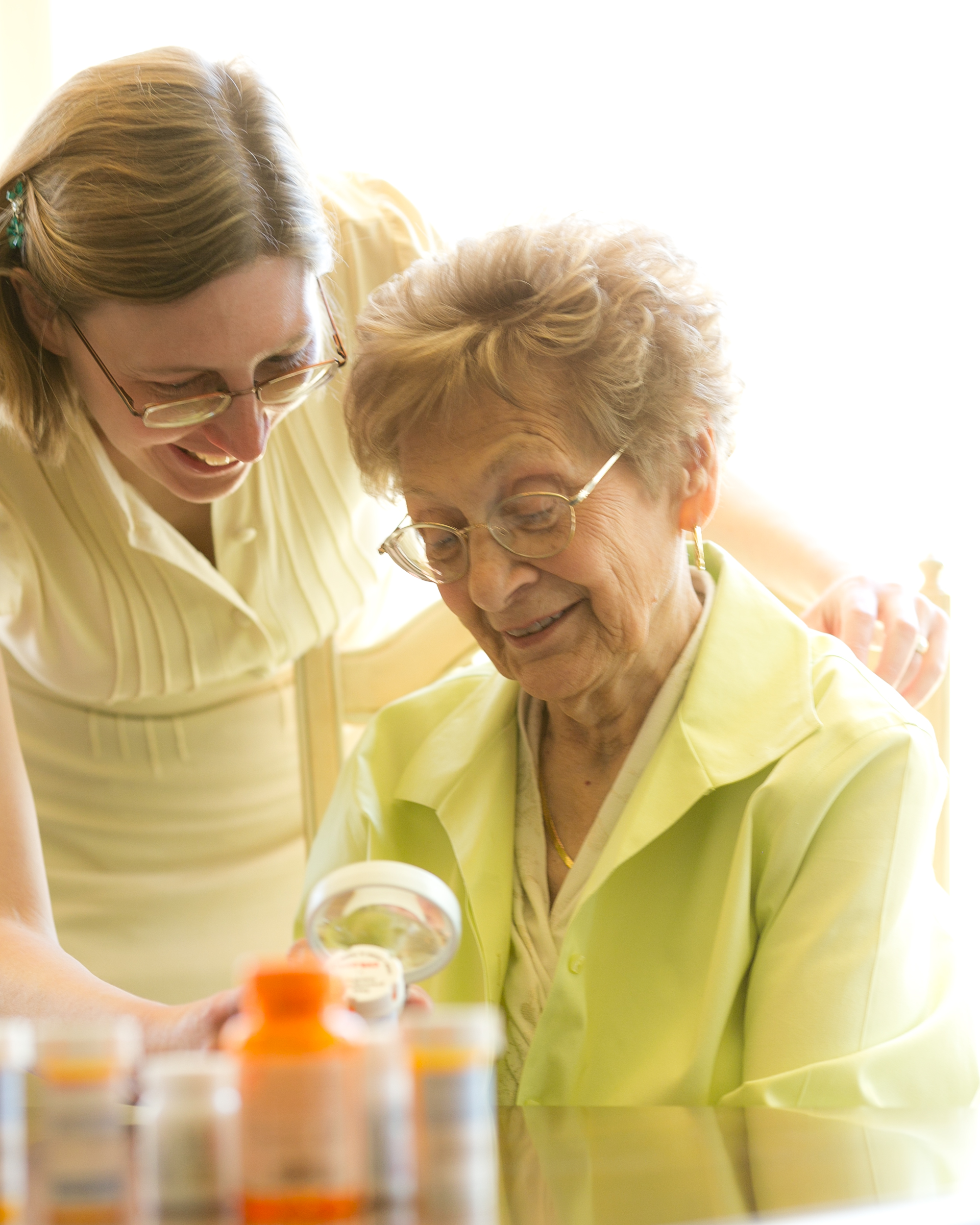 a younger woman helping an older woman read a prescription label
