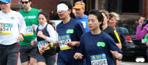 a blindfolded runner runs with her guide