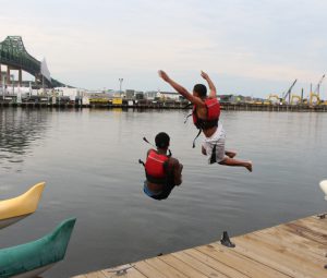 Two special needs students from Ivy Street School jump off a dock into the water