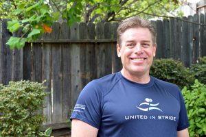 Richard Hunter smiling for the camera outside wearing a United in Stride t-shirt