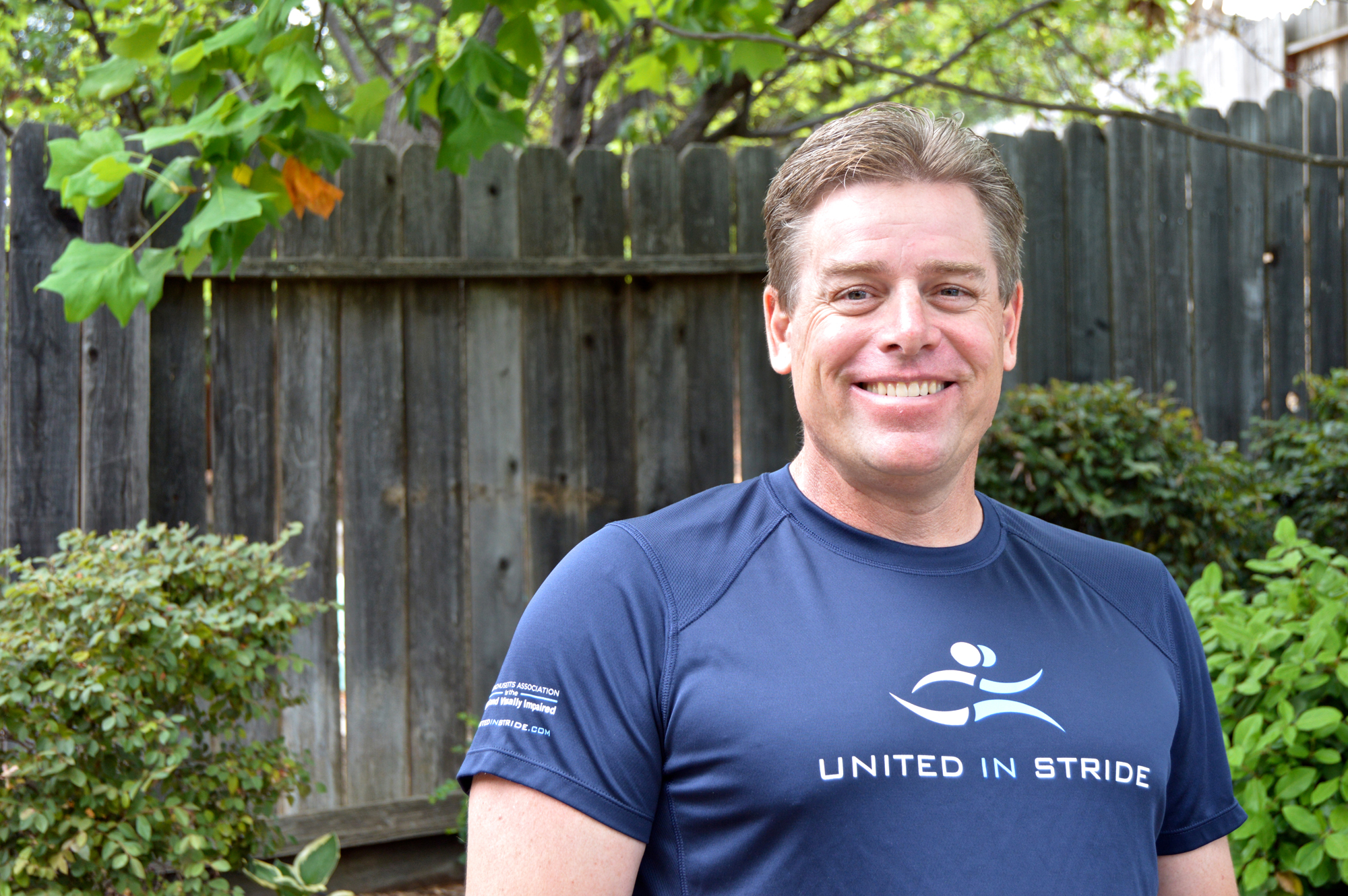 Richard Hunter smiling for the camera outside wearing a United in Stride t-shirt
