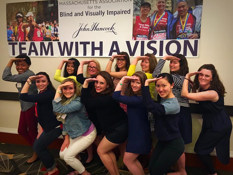 Delta Gamma sisters give the DG salute in front of a MABVI Team With A Vision banner