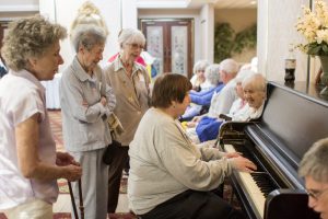 A Senior Connection attendee plays the piano while others sing along