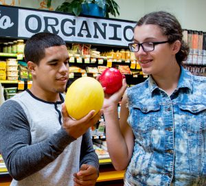 An Ivy Street School student shopping for fruit in a grocery store with a teacher