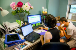 Woman and a student sitting at a desk looking at computer screens
