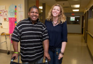 a man walking with a walker next to a woman assisting him