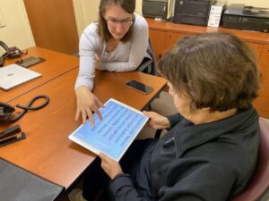 Image of a MABVI employee showing a woman how to use an iPad with enlarged font