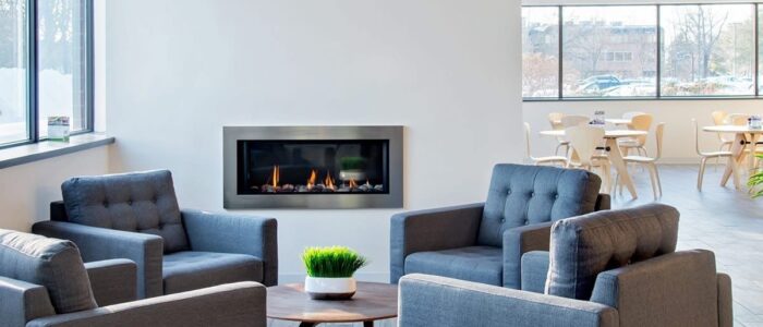 Four dark colored armchairs arranged in a circle with an electric fireplace in the background.